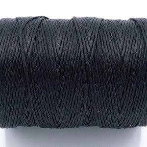 Puede incluir: Un carrete de hilo negro, enrollado con fuerza. El hilo es de un material texturizado y est&aacute; dispuesto en un patr&oacute;n entrecruzado. El fondo es blanco liso. Ideal para manualidades.
