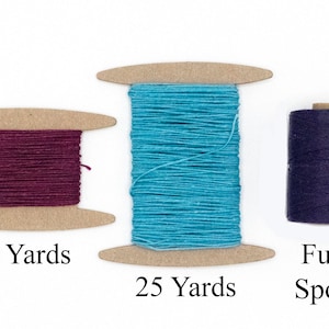 May include: Three spools of thread in varying colors. One spool is a deep burgundy with "10 Yards" printed below. The second spool is turquoise with "25 Yards" printed below. The third spool is dark blue with "Full Spool" printed below.