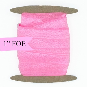 May include: A spool of 1" pink fold over elastic (FOE) on a brown cardboard spool.