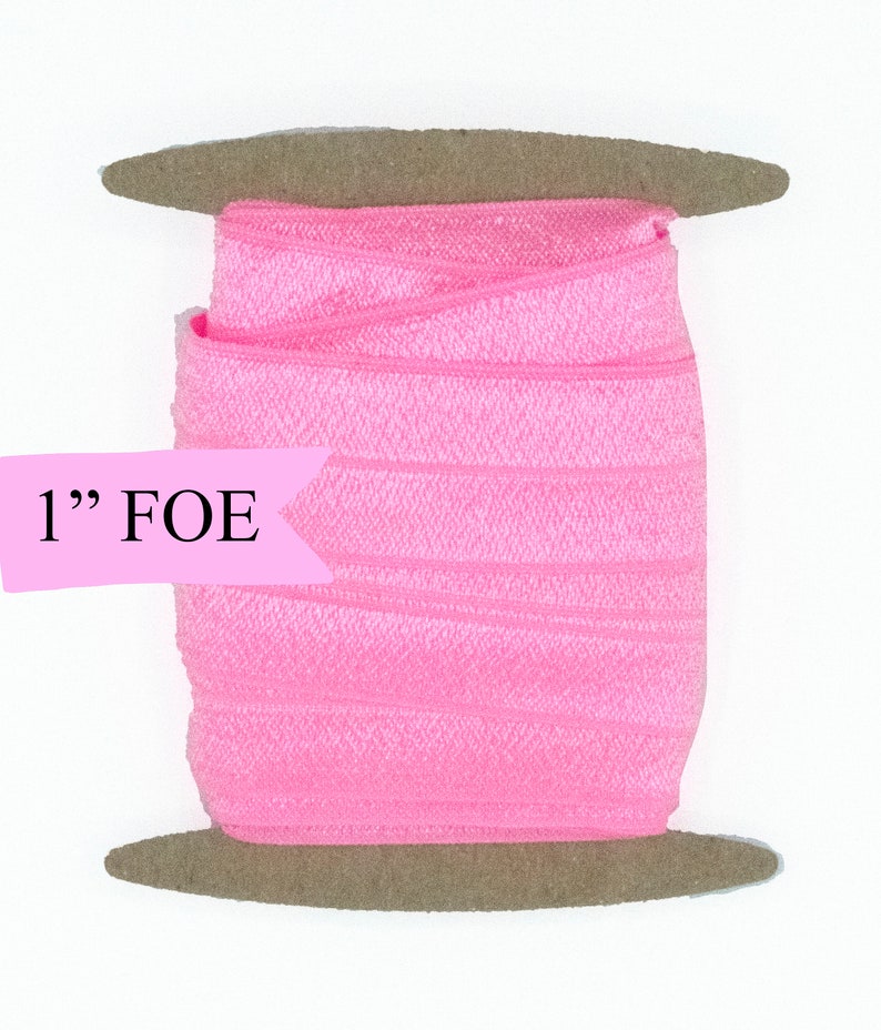 May include: A spool of 1" pink fold over elastic (FOE) on a brown cardboard spool.