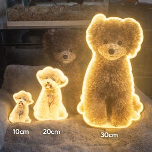 May include: Three illuminated dog-shaped lamps of varying sizes, 10cm, 20cm, and 30cm tall, are arranged on a soft, gray surface. The lamps have a warm, glowing outline and a fluffy, textured appearance, resembling a poodle.