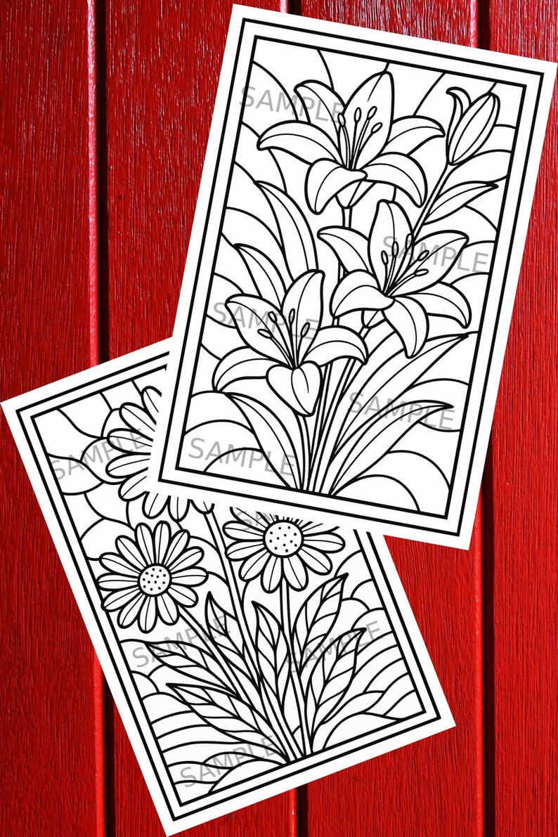 May include: Two black and white floral coloring pages featuring lilies and daisies. The images are in a rectangular frame with the word "SAMPLE" printed on them. The background is a red wooden surface.
