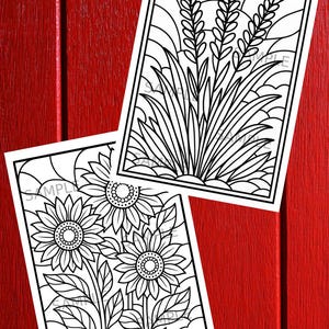 May include: Two black and white line art coloring pages featuring botanical illustrations. One depicts sunflowers, the other shows wheat. The pages are rectangular with a white border and are set against a red wooden background.