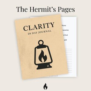 May include: A journal titled "CLARITY 28 DAY JOURNAL" with a lantern graphic. The journal is tan with black text and a black lantern illustration. A second page with lined paper is visible behind the journal. The words "The Hermit's Pages" are at the top.