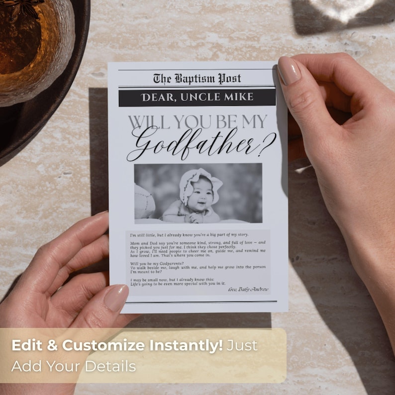 May include: A black and white newspaper-style card with the headline "The Baptism Post" and the text "Dear, Uncle Mike, Will You Be My Godfather?" A baby's photo is in the center. The card is held by hands.
