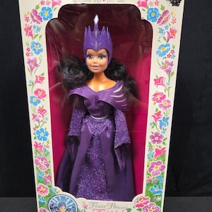 May include: A vintage doll in a box. The doll is a Flower Princess Fairytale Witch, Tempestia, with soft movable arms and bendable legs. The doll is 29.2 cm tall and wears a purple dress and crown. The box has floral designs.