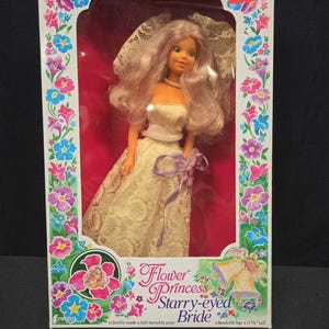 May include: A vintage doll in a box, labelled "Sparkling Eyes" and "Flower Princess Starry-eyed Bride." The doll has long, light purple hair, a white dress, and a veil. The box is decorated with floral designs and the doll is 29.2 cm tall.