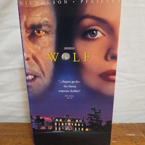May include: A VHS tape for the movie "Wolf" featuring Jack Nicholson and Michelle Pfeiffer. The cover art shows a close-up of the actors' faces and a mansion at night. The text includes the movie title and a quote.