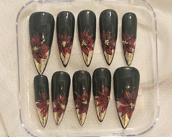 Uñas navideñas pintadas a mano: stiletto largo verde con flor de Pascua roja
