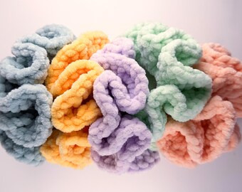 May include: A collection of colorful, plush scrunchies in various pastel shades. The scrunchies are in shades of blue, yellow, purple, green, and peach. The soft, textured fabric is bunched together, creating a voluminous appearance. These hair accessories are ideal for adding a pop of color.