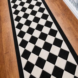 May include: A rectangular runner rug with a black and white checkered pattern. The rug has a black border and is placed on a wooden floor. The design is a classic checkerboard, creating a bold visual statement.