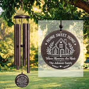 Könnte beinhalten: Ein bronzefarbenes Metall-Windspiel mit sechs zylindrischen Röhren und einem runden Windfänger. Der Windfänger ist mit einer Hausillustration sowie dem Text "HOME SWEET HOME", "Where Memories Are Made" und "The Johnson Family" graviert.