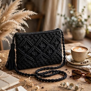 May include: A black macrame crossbody bag featuring a diamond-patterned knot design on the front, a long braided shoulder strap, and a decorative tassel attached to the side. The bag is constructed from cord with a textured, knotted finish.