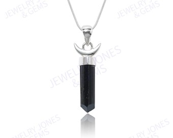 Puede incluir: Un collar de plata con un colgante de cristal de turmalina negra. El colgante tiene un diseño de media luna plateada sobre el cristal. El collar se muestra sobre un fondo blanco. Joyas de Jewelry Jones & Gems.