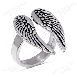 Puede incluir: Un anillo plateado con un dise&ntilde;o abierto, con dos alas de &aacute;ngel estilizadas. Las alas tienen patrones de plumas grabadas y la banda del anillo es lisa y pulida. Esta joya es un accesorio decorativo.