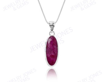 May include: A silver pendant necklace with a large, oval ruby gemstone. The ruby is a deep red colour, set in a silver bezel. The necklace hangs from a delicate silver chain. The image includes the text "JEWELRY JONES & GEMS".