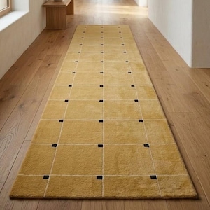 May include: A long, rectangular runner rug in a mustard yellow hue, featuring a grid pattern defined by thin white lines and small, solid black squares positioned at each intersection of the grid across the entire surface of the textile.