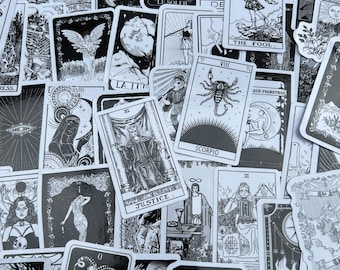 May include: A collection of black and white tarot cards featuring various illustrations and text. The cards depict celestial bodies, figures, and symbols, including "The Star," "The Fool," and "Justice." The cards are scattered across a surface.