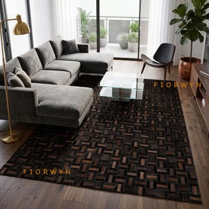 Peut inclure: Un tapis rectangulaire présentant un motif géométrique en patchwork de couleur marron foncé et noir, composé de carreaux individuels. Le tapis affiche le texte FIORWYN en lettres dorées dans deux coins et recouvre une grande partie du parquet.