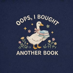 Könnte beinhalten: Marineblau besticktes Sweatshirt mit einer weißen Gans mit rosa Schleife, die Bücher trägt. Der Text lautet "OOPS, I BOUGHT ANOTHER BOOK" in Weiß, mit Blumen- und Sternakzenten.