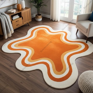 May include: A distinctive area rug with a retro design. The rug has an organic shape and features an orange centre, with yellow and white bands. The rug measures approximately 152 cm by 203 cm.