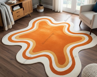May include: A retro-style area rug with a unique, organic shape. The rug features a vibrant orange center, bordered by bands of yellow and white. The rug's dimensions are approximately 60 inches by 80 inches.