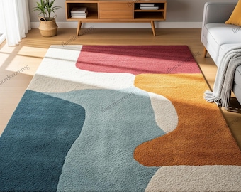 May include: A large, rectangular rug with an abstract design in shades of red, white, blue, yellow, and orange. The rug's flowing, organic pattern sits on a wooden floor. The rug's design and colour palette create a modern and inviting atmosphere in the room.
