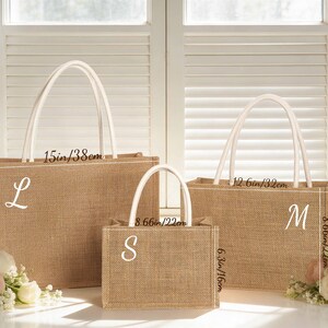 May include: Three burlap tote bags of varying sizes, each with white handles and a white initial. The largest bag is 15 inches wide and 10.6 inches tall. The medium bag is 12.6 inches wide and 8.66 inches tall. The smallest bag is 8.66 inches wide and 6.3 inches tall.