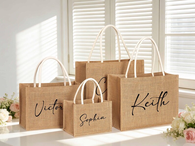 May include: A collection of burlap tote bags with white handles. Each bag has a name printed in black script: Victor, Sophia, Keith. The bags are in various sizes and are likely for a special event or gift.