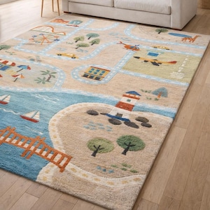 May include: A rectangular children's rug with a playful road map design. The rug features a light beige background with blue, green, and orange illustrations of roads, buildings, a lighthouse, and vehicles. The rug is placed on a wooden floor.
