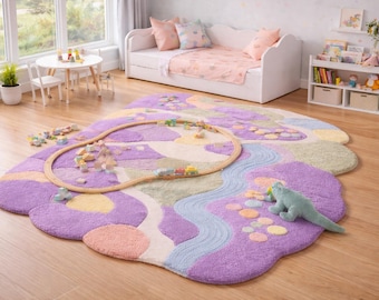 Puede incluir: Una alfombra caprichosa en forma de nube, en tonos morados, rosas y verdes, con una vía de tren de madera y un juguete de dinosaurio de peluche. La alfombra está colocada sobre un suelo de madera en la habitación de un niño, con un sofá cama blanco y una mesita en el fondo.