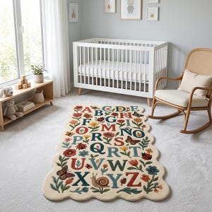 May include: A cream-colored nursery rug with a scalloped edge features the alphabet in colorful letters. The letters are surrounded by floral and insect illustrations, including butterflies, ladybugs, and snails. The rug is placed in a nursery setting with a white crib and rocking chair.