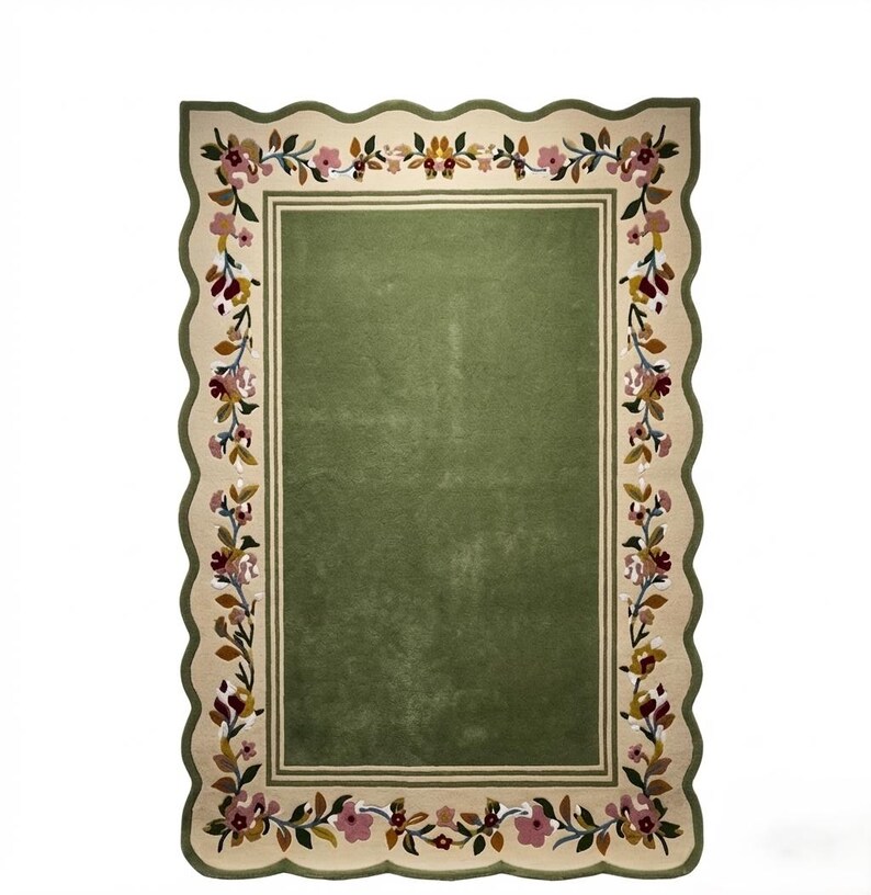 May include: A rectangular rug with a scalloped edge, featuring a solid olive green centre framed by a cream-coloured border. The border is decorated with a continuous floral vine pattern in shades of pink, burgundy, brown, and dark green.