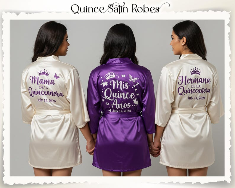Three satin robes are shown, two in ivory and one in purple. The ivory robes feature the text "Mama de la Quinceañera" and "Hermana de la Quinceañera" on the back, with the date "July 14, 2024". The purple robe says "Mis Quince Años" with the same date.