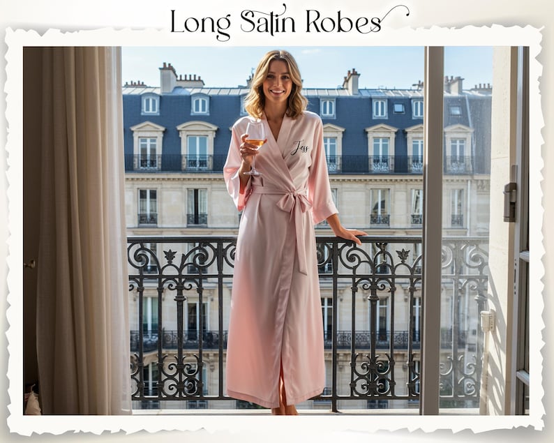 May include: A light pink satin robe with a matching tie, personalized with the name "Jess" in black script. The robe is knee-length and has wide sleeves. The text "Long Satin Robes" is at the top of the image.