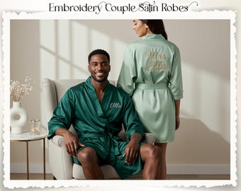 May include: Emerald green and pale green satin robes. The emerald robe has "Ellis" embroidered in white on the front. The pale green robe has "Mrs Ellis" embroidered in gold on the back. The robes are tied at the waist.