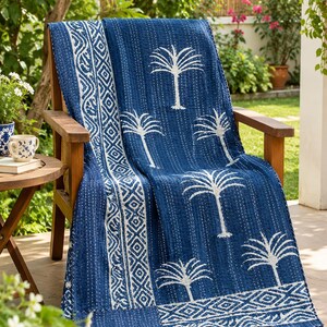Könnte beinhalten: Eine tiefblaue Baumwolldecke mit einem weißen Palmenmuster und geometrischen Bordüren. Das Textil weist durchgehend sichtbare weiße Steppstichdetails auf, die dem gesamten Stoff ein strukturiertes Aussehen verleihen.