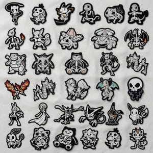 Puede incluir: Una colección de parches bordados en blanco y negro con varios personajes de dibujos animados con temática de esqueletos. Los parches son de diferentes formas y tamaños, con costuras detalladas y una variedad de diseños.