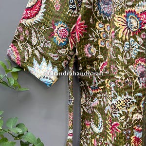 May include: Olive green quilted robe with a vibrant floral pattern in pink, blue, and yellow. The robe features a tie closure and short sleeves. The text "chandrahandicraft" is visible on the robe.
