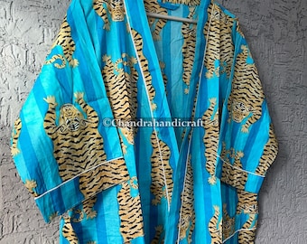 May include: A blue and yellow tiger-print robe with vertical stripes. The robe has a white trim and is hanging on a wooden hanger. The robe is made of a lightweight fabric.