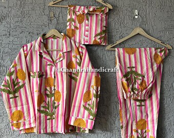 Op de afbeelding: Een driedelige pyjamaset met een roze en wit gestreept patroon. De set bevat een shirt met lange mouwen en knopen, een broek en een bijpassend zakje. De pyjama's hebben een bloemenmotief in geel en groen.