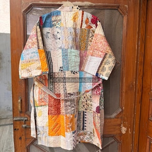 May include: A long-sleeved robe featuring a patchwork design composed of various fabric squares in shades of blue, yellow, orange, red, and white. The garment includes a matching tie belt and visible running stitch quilting throughout the fabric.