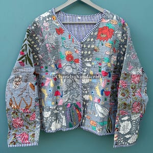 May include: A gray quilted jacket with a V-neck and long sleeves. The jacket features a floral and animal print in various colors, including red, pink, and blue. The interior lining is striped. The text "Chandrahandicraft" is visible.