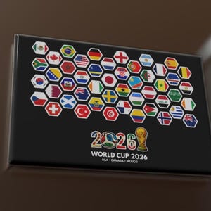 Puede incluir: Una placa rectangular negra con un mosaico de banderas hexagonales que representan varios países. Debajo de las banderas, se muestra el texto "2026 COPA MUNDIAL", junto con los países anfitriones: EE. UU., Canadá y México. También hay un trofeo dorado.