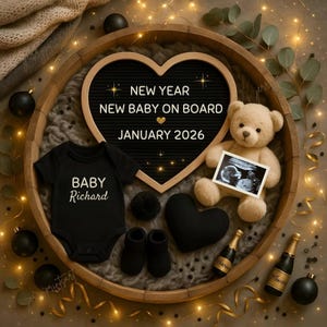 Può includere: Un body nero con la scritta "BABY Richard", scarpine e un orsacchiotto che tiene un'immagine ecografica sono disposti in un vassoio di legno. Un cartello a forma di cuore recita "NEW YEAR NEW BABY ON BOARD JANUARY 2026."