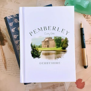 May include: A white book with the text "Pemberley Country Estate - Derbyshire" and a watercolour image of a large house with a lake in front of it.