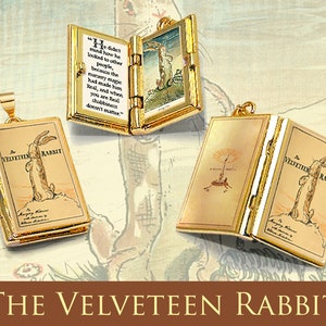 Puede incluir: Colgantes dorados con forma de libros en miniatura, con ilustraciones y texto de "El Conejo de Terciopelo". Uno está abierto, mostrando una cita y una imagen. Los otros muestran la portada del libro.