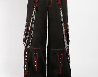 Puede incluir: Pantalones cargo negros con costuras y detalles en rojo. Los pantalones presentan tachuelas plateadas, cadenas y correas. Cuentan con múltiples bolsillos y cintura con cordón. El diseño es de pierna ancha, de estilo punk o alternativo.