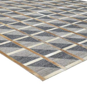 May include: A geometric rug with a repeating diamond pattern in grey, white, and tan. The rug's design creates a textured appearance, suitable for various interior styles. The rug is made of a soft material, suitable for living rooms.