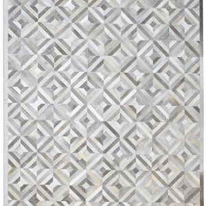 Könnte beinhalten: Ein rechteckiger Teppich mit geometrischem Muster. Der Teppich hat ein Patchwork-Design aus Quadraten und Rauten in Grau-, Weiß- und Beigetönen. Das Muster erzeugt ein strukturiertes Aussehen, geeignet für die Inneneinrichtung.